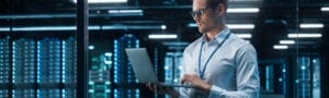 Portrait of IT Specialist Uses Laptop in Data Center Server Far