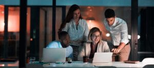Research, laptop and business people in office at night with stock market charts for corporate investment Discussion, computer and financial advisors working on company profit report with deadline